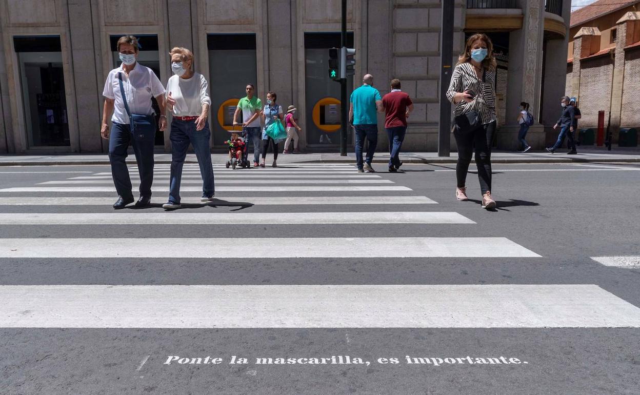 Varias personas cruzan por un paso de peatones.