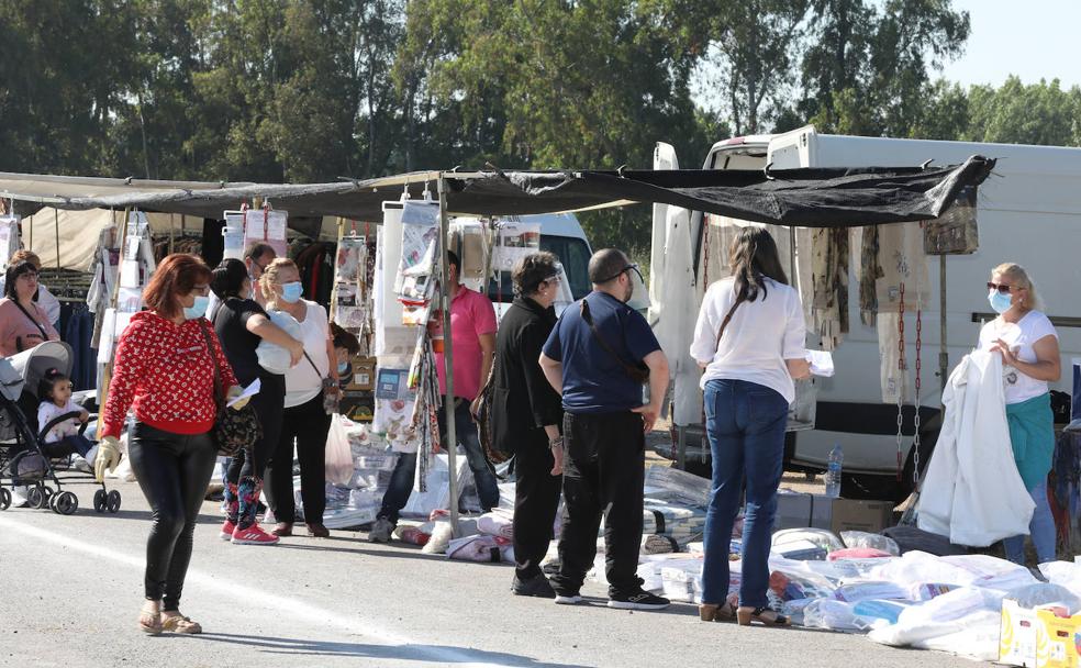 Clientes y curiosos pasan ante uno de los puestos del mercadillo de Mérida. 