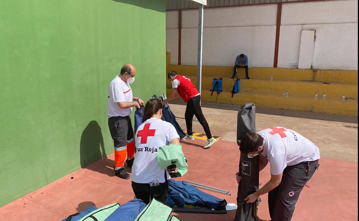 Personal de Cruz Roja recogiendo material en el pabellón deportivo. 