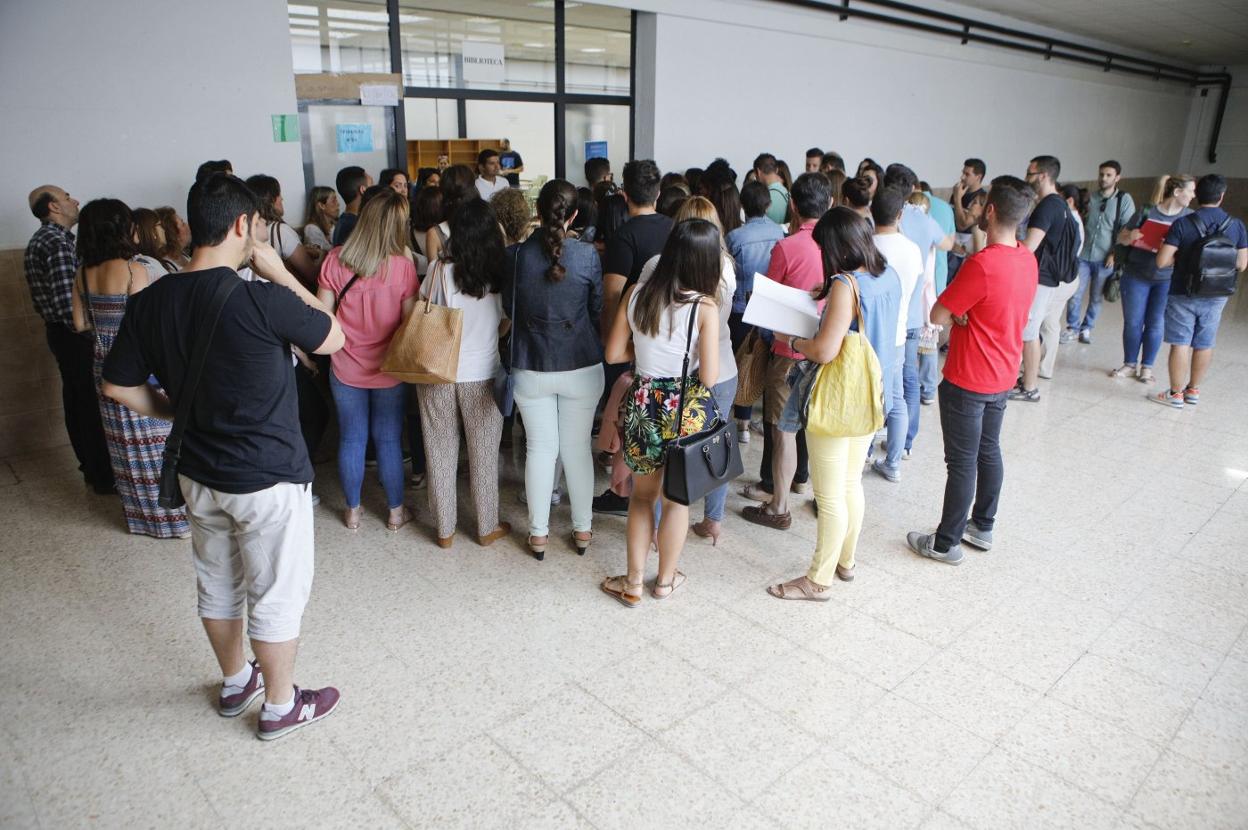 Aspirantes esperan a entrar en el aula en unas oposiciones. 