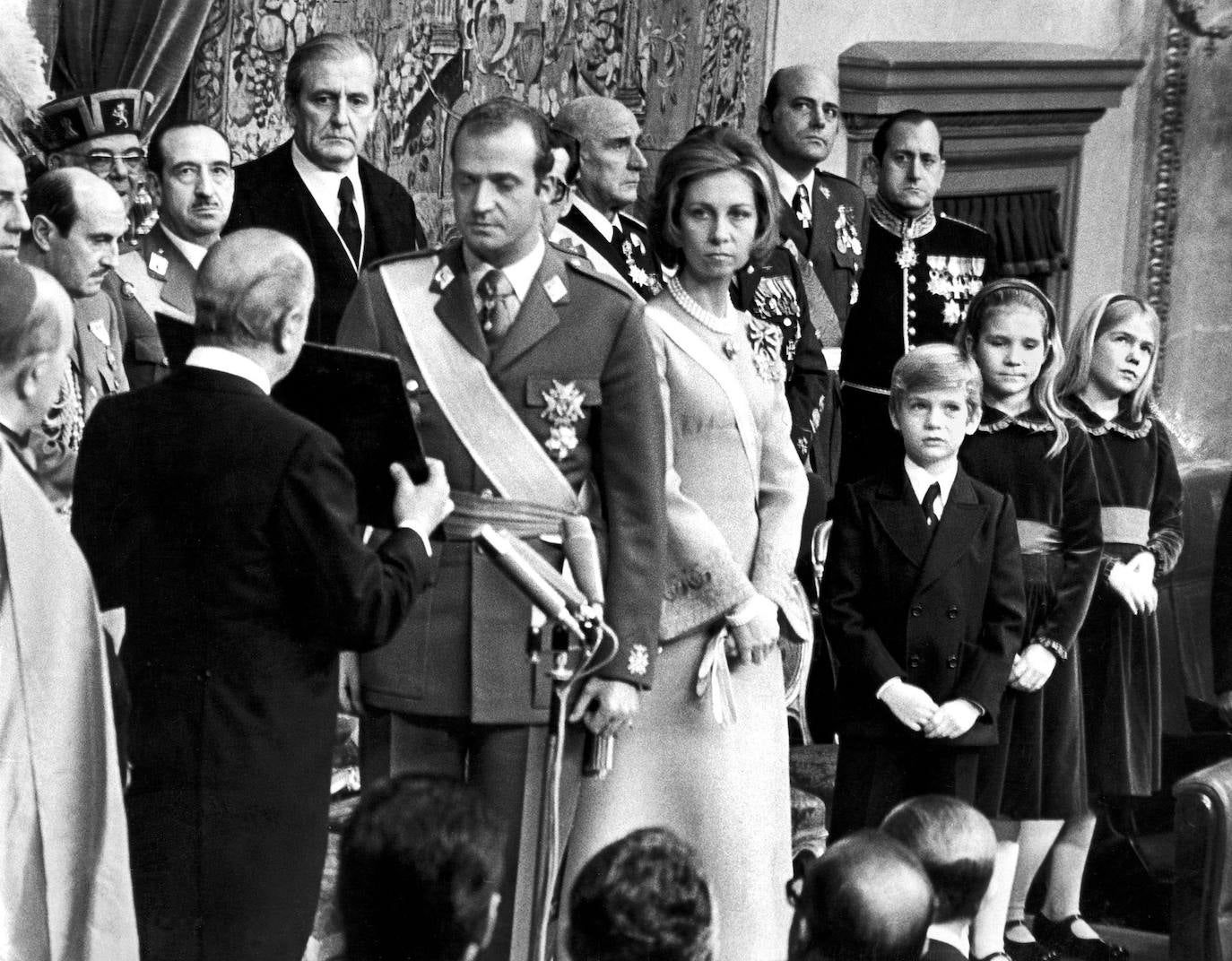 1975. Juan Carlos jura las Leyes ante el presidente de las Cortes, Alejandro Rodríguez de Valcárcel, y es proclamado Rey de España (a la izda., de frente y con bigote, el general Alfonso Armada).