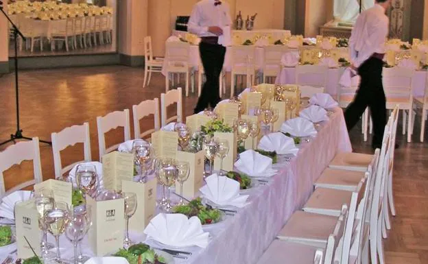 Camareros de un restaurante preparan las mesas para una celebración de boda.