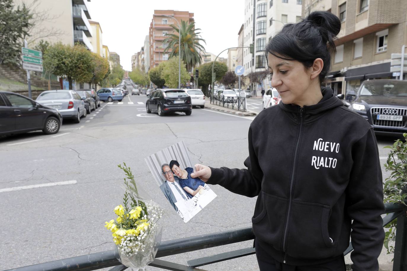 Gema Silveira mirando una foto en la que aparece su padre, que falleció el 31 de marzo. Lo hace desde la Plaza de Colón de Cáceres, donde le llevan flores porque era su lugar favorito. 