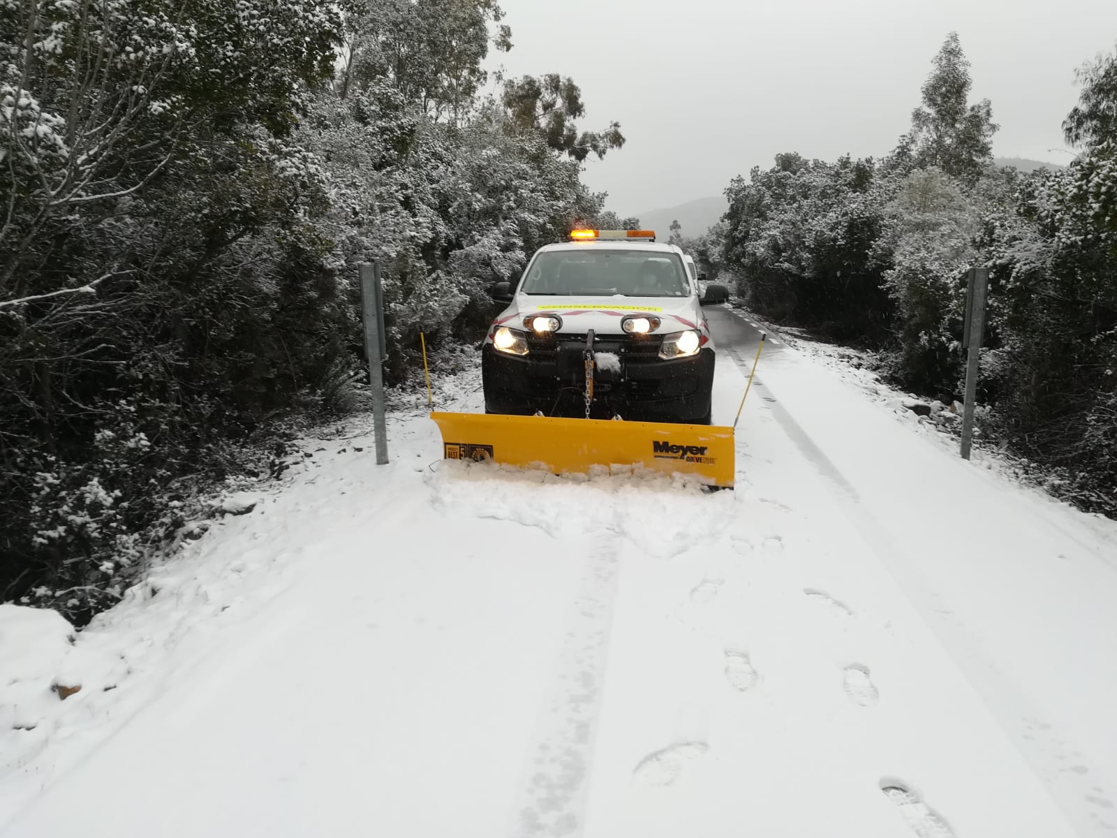 Un vehículo retira la nieve en la carretera CC 20.2 Villar del Pedroso a ex 118