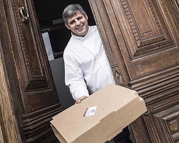 David Núñez, del restaurante El Sigar, con uno de sus paquetes en la puerta.