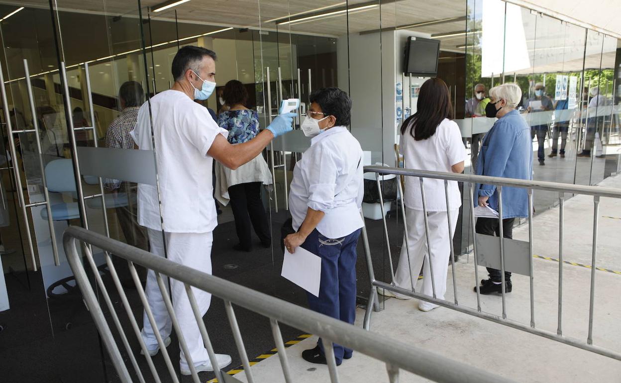 Un sanitario tomando la temperatura antes de vacunar en el Palacio de Congresos de Cáceres.