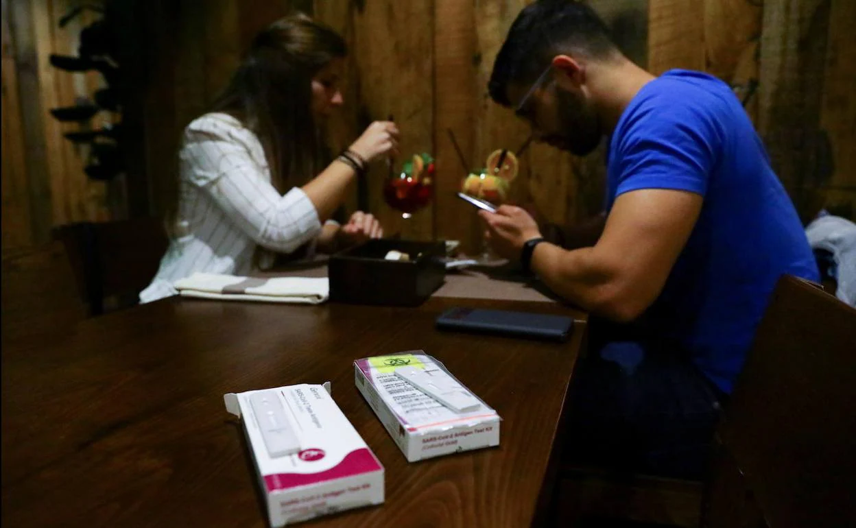 Una pareja toma un cóctel en el interior de un local de Oporto con sus test rápidos sobre la mesa.