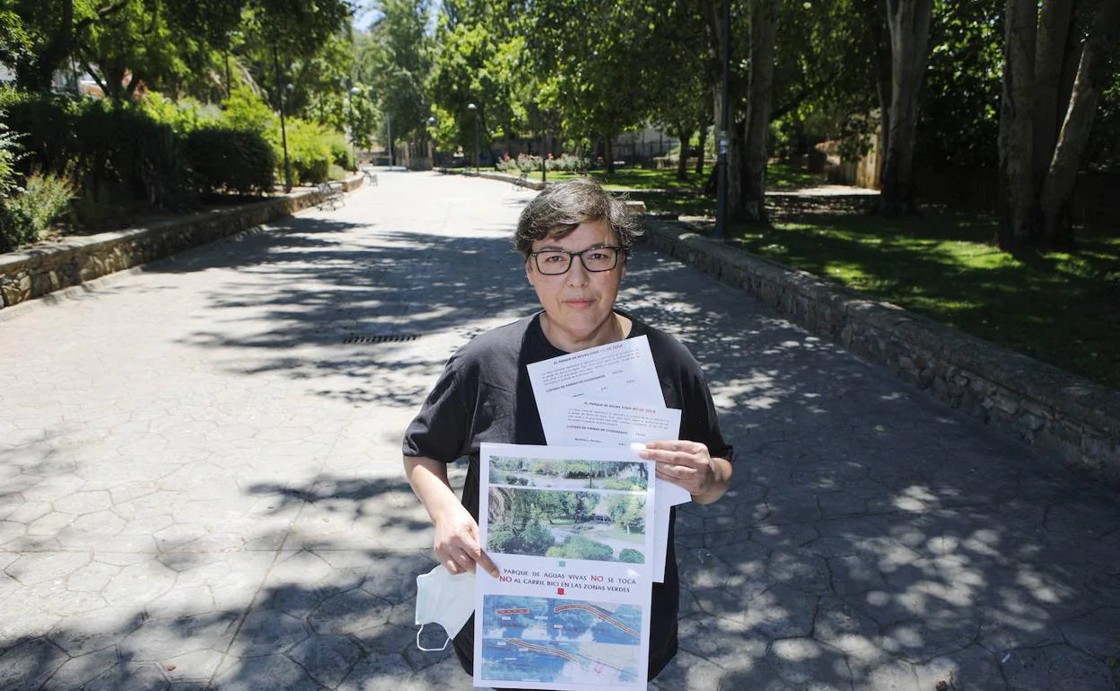 María José Rodríguez, muestra los carteles que ha hecho para protestar por el trazado del carril bici. Posa en la calzada de cemento que hay junto a la zona ajardinada. 