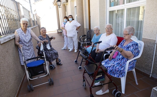 Varias usuarias de la residencia de Santiago del Campo, junto a dos trabajadoras, toman el fresco y pasean en el patio.