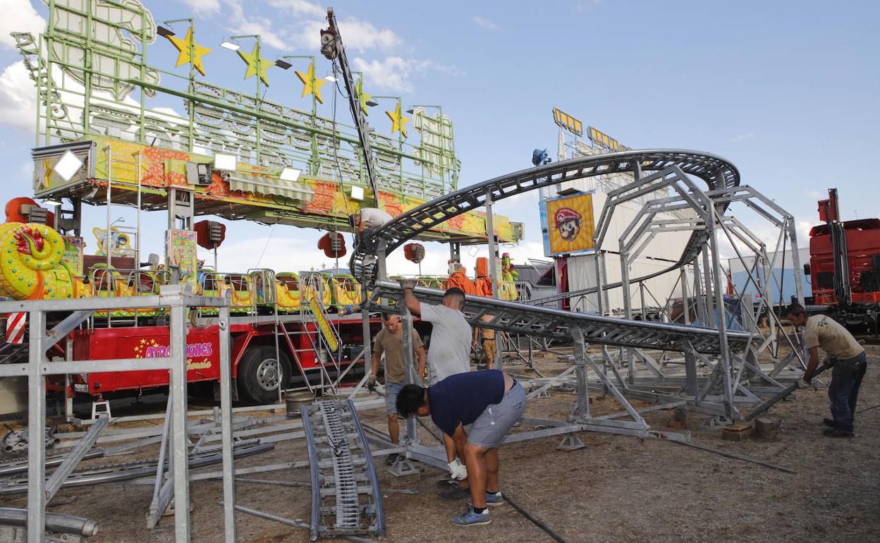 Feriantes montando la atracción 'El nuevo dragón Elliot', en la tarde de este miércoles en el ferial de Cáceres. 