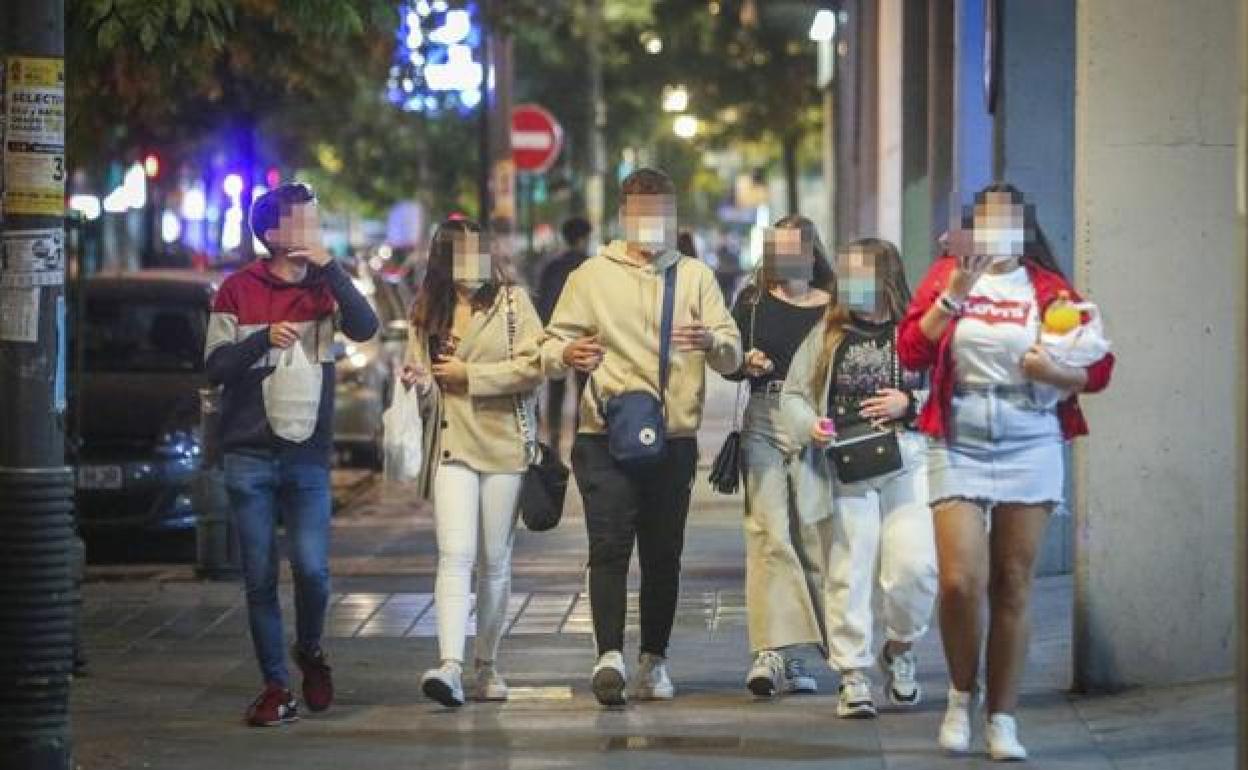 Jóvenes caminan por una calle de Granada. 