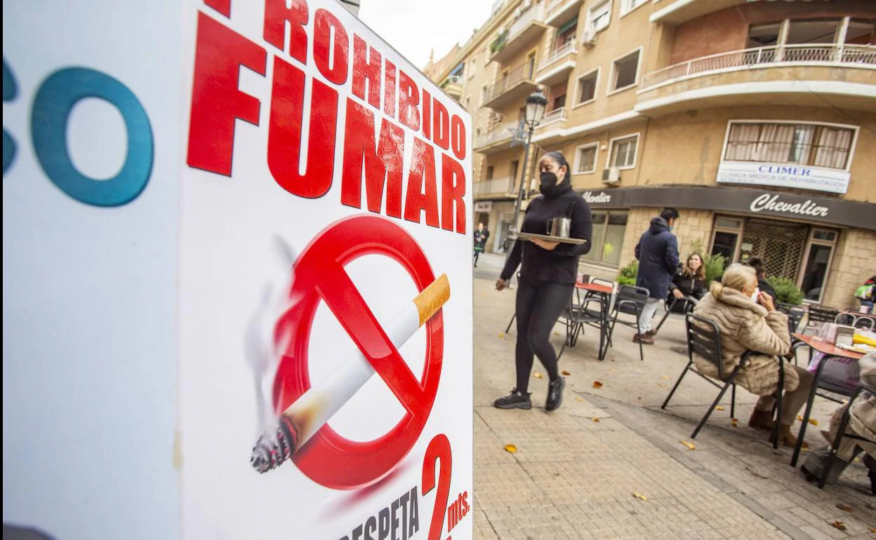 Una terraza de Cáceres con un cartel que indica que solo se puede fumar si hay distancia de dos metros.