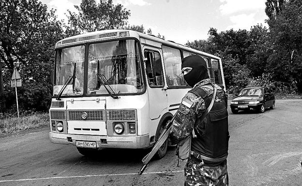 A Ukrainian soldier checks buses at an intersection near the front line