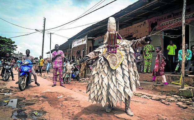 Imagen principal - 1- El reino de la superstición. Un fetiche despliega sus artes en un arrabal paupérrimo de Porto Novo, capital de Benín. 2- Realismo mágico. Niños juegan ante la fachada de una casa que reproduce las fauces de un león en Savalou 3-Escenario de pesadilla. El sacerdote del Templo de las Pitones luce escarificaciones que simulan mordeduras