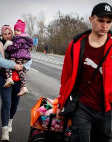 Imagen secundaria 2 - Arroba. Primeros fallecidos. Un vecino de Chuguev, al este de Ucrania, tapa con una manta a una víctima de los ataques rusos. Debajo. Bombardeos. Un hombre herido en Járkov; y una familia camina a la frontera con Hungría. 