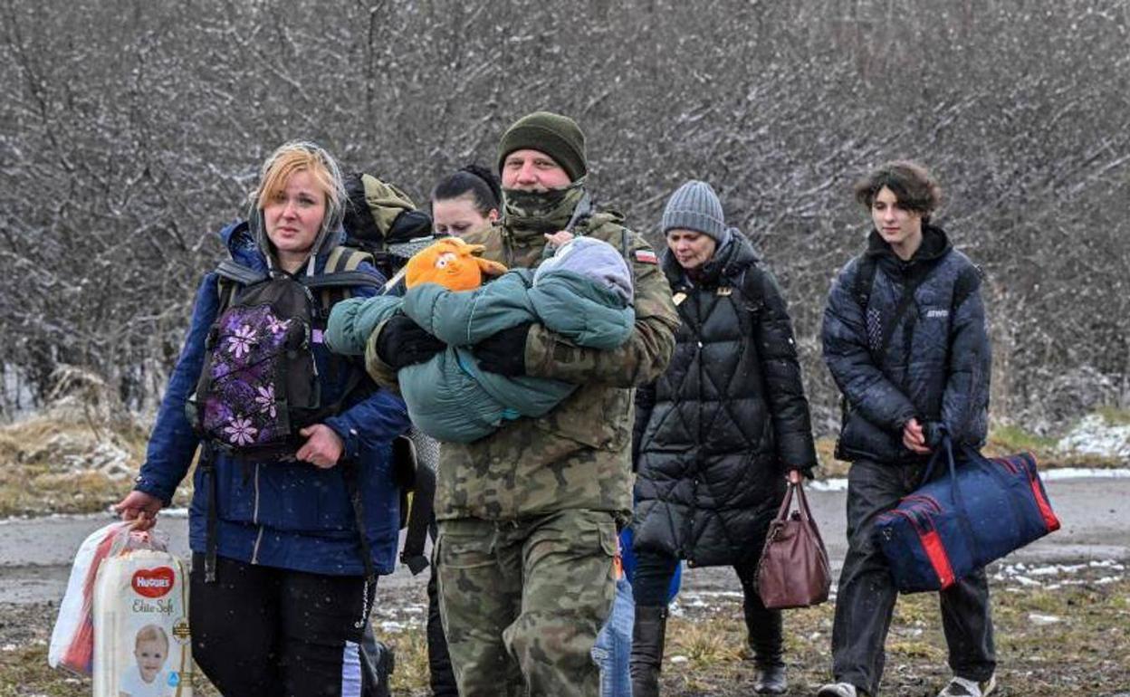 Un soldado polaco ayudando a una familia ucraniana después de cruzar la frontera con Polonia. 