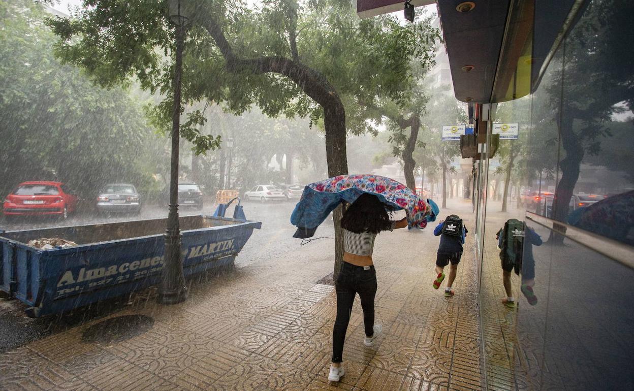 Personas intendan resguardarse de la tormenta en Extremadura.