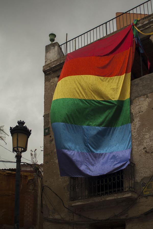 Una gigantesca bandera arcoíris envuelve un torreón en la fiesta de Los Palomos de Badajoz.