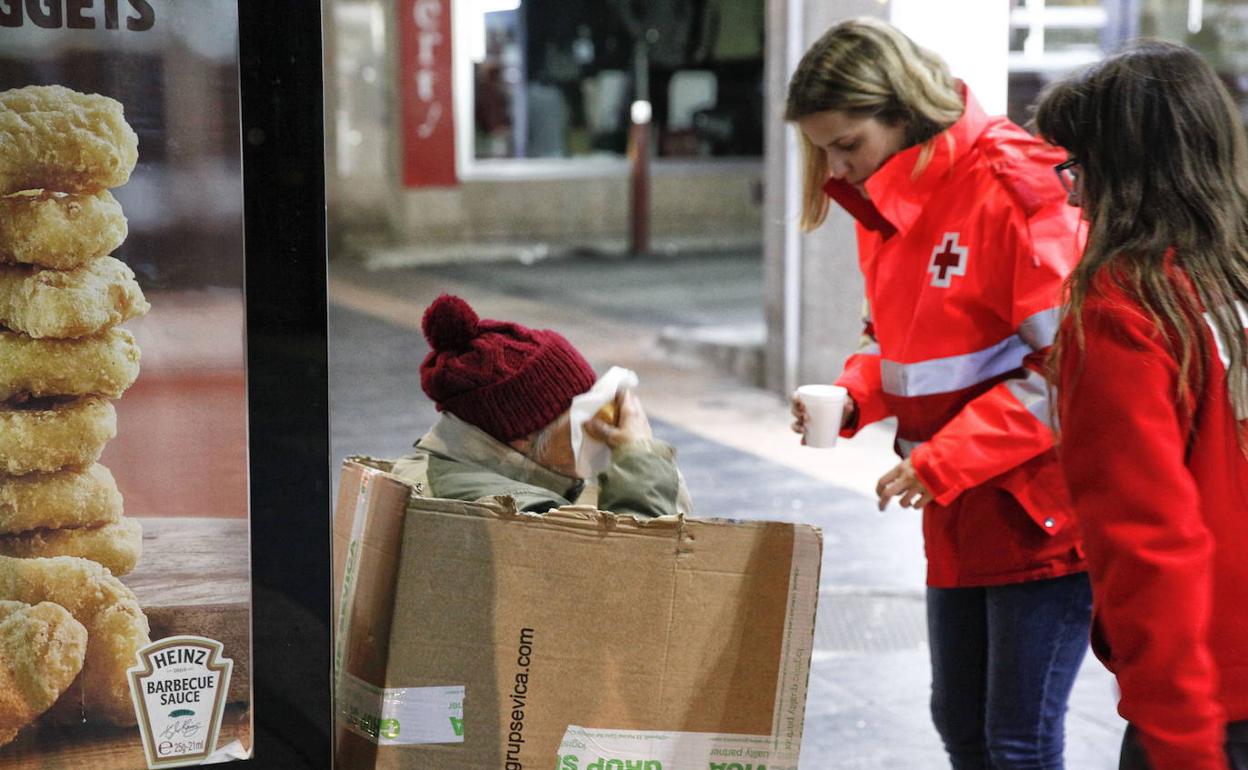 Imagen de archivo de voluntarias de Cruz Roja con una persona sin hogar durante un protocolo de la ola de frío. 