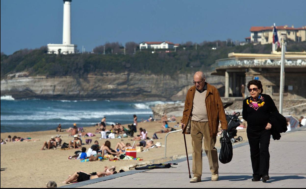 Dos jubilados pasean frente a una playa. 