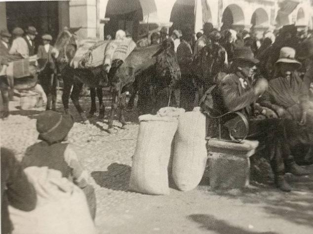 Vendedora de patatas junto a sacos y un carro.
