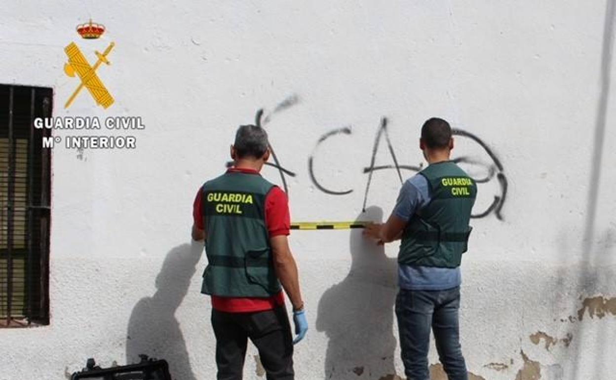 Agentes de la Guardia Civil examinan una de las pintadas realizadas en Riolobos. 