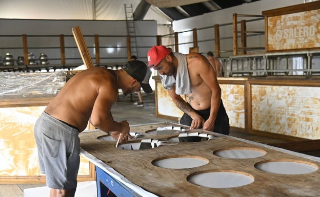 Trabajadores sin camiseta montando la caseta El Salero, este lunes. 