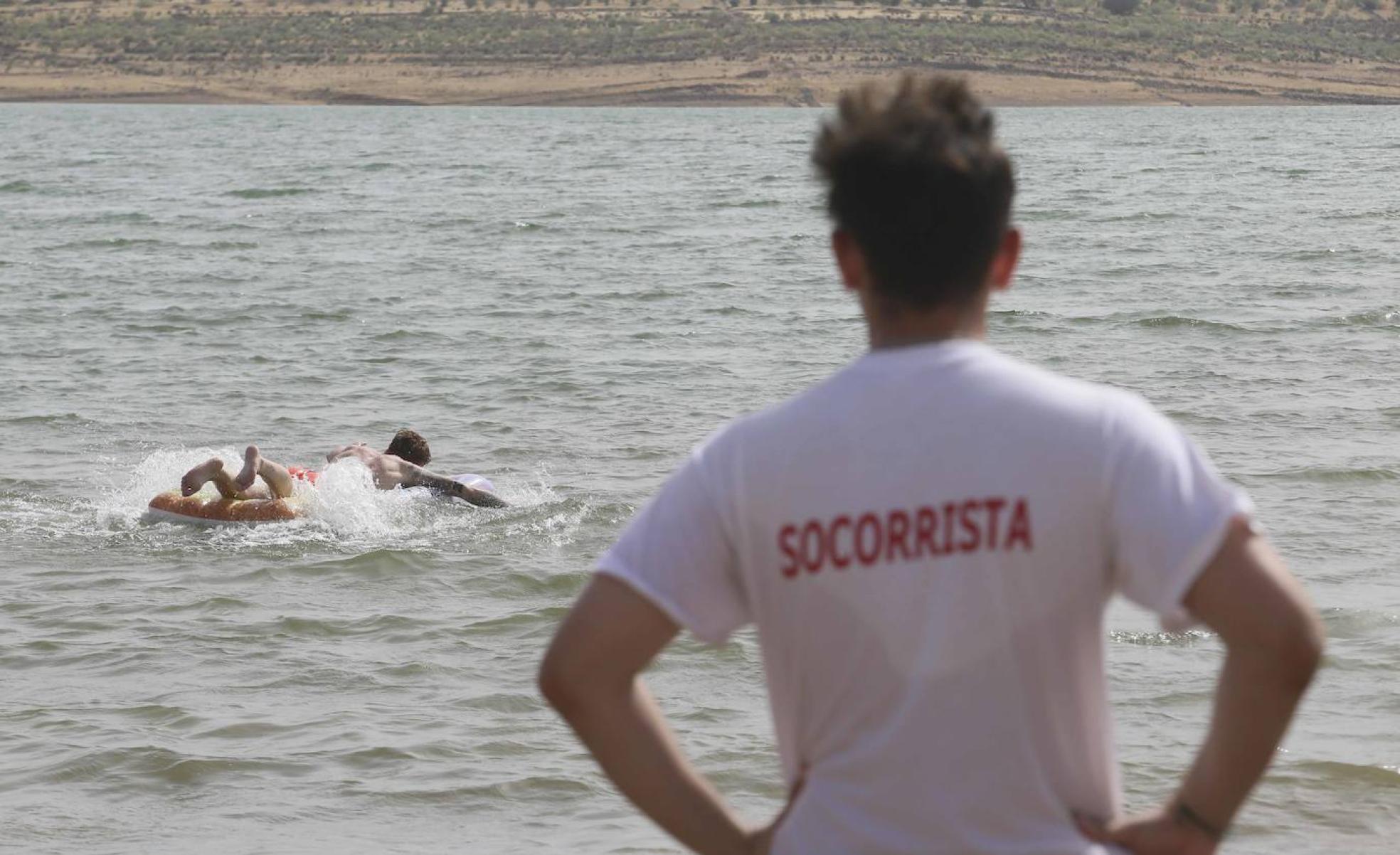 Un socorrista vigila a un bañista en la playa de Alange. 
