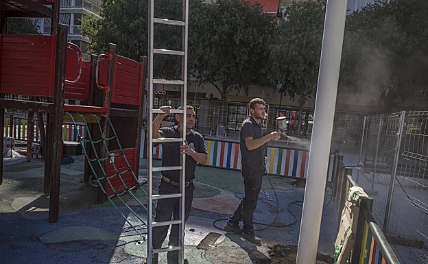 Trabajadores colocan los postes de sombra para los columpios. 