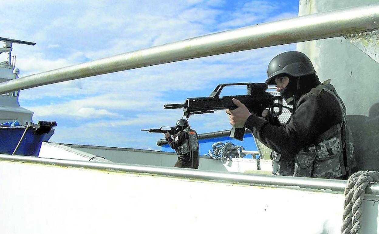 Disparos de advertencia contra un esquife pirata en aguas de Somalia. Abajo, curso de adiestramiento para vigilantes de seguridad en alta mar. 