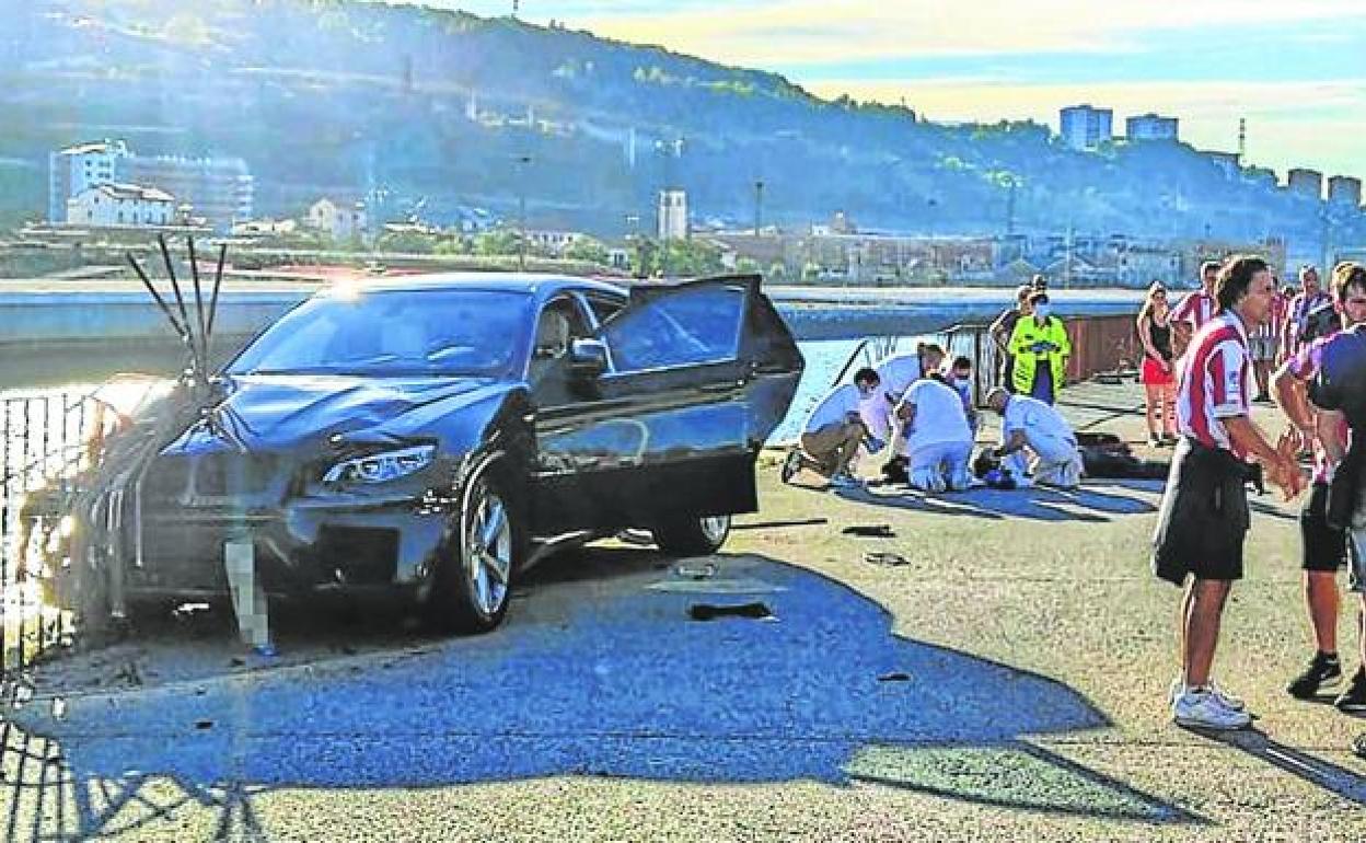 Sanitarios atienden a la víctima instantes después de ser arrollada por el coche, que a punto estuvo que caer a la ría.