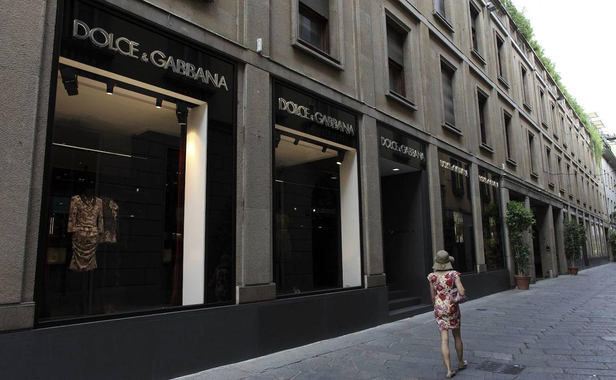 Una mujer pasea junto a una tienda de ropa de lujo. 