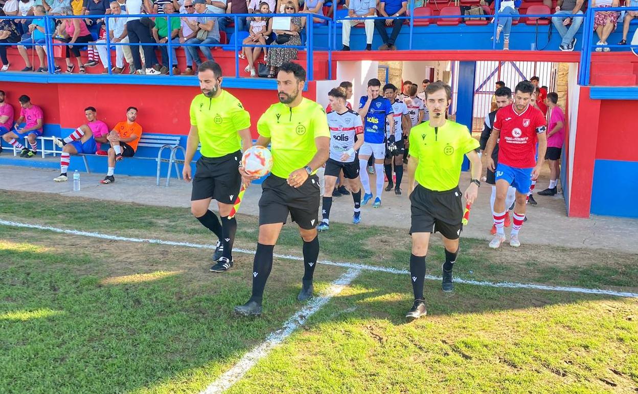 Los capitanes y jugadores del Pueblonuevo y Miajadas salen de vestuarios tras el equipo arbitral encabezado por Galayo Castro. 