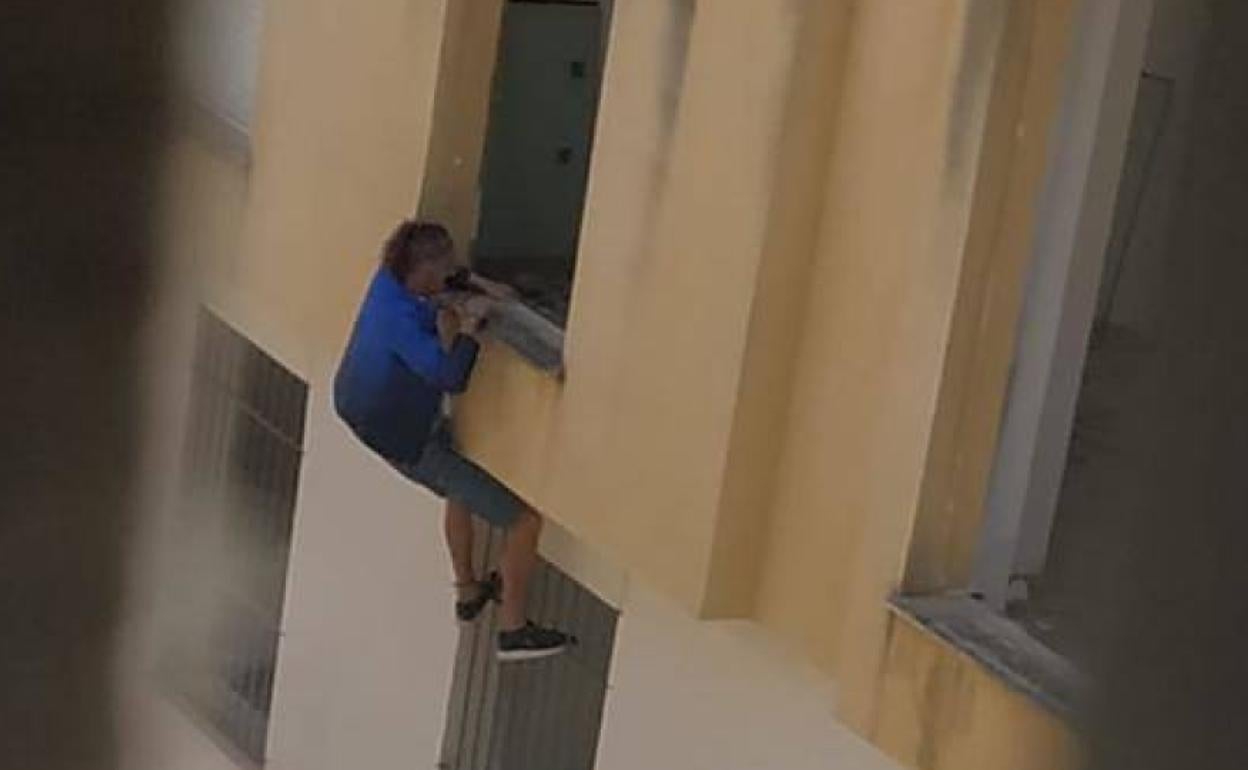 Un hombre trepa por la fachada para acceder al inmueble, dado que los bajos están tapiados o con rejas. 