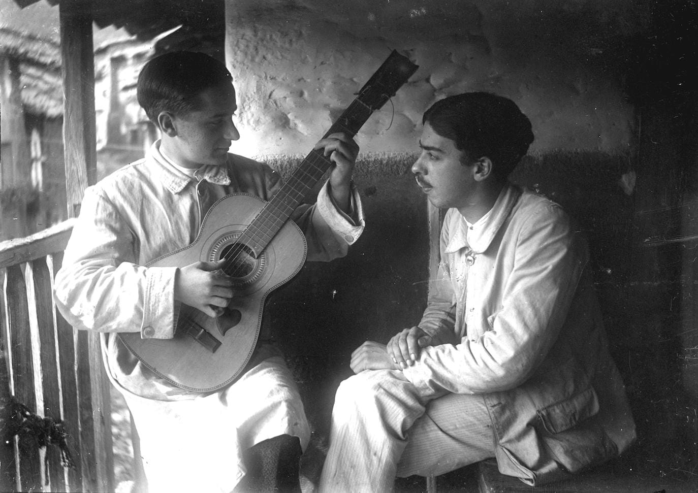 José Alfaro tocando la guitarra en un balcón de Hoyos junto al hermano de su novia Elisa.