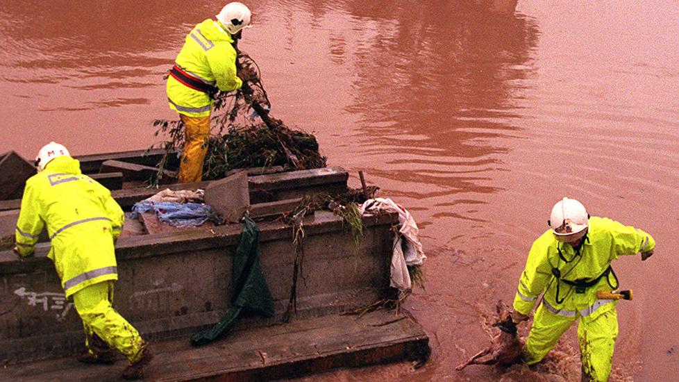 Tres bomberos registran los restos de la pasarela derruida en busca de cuerpos.