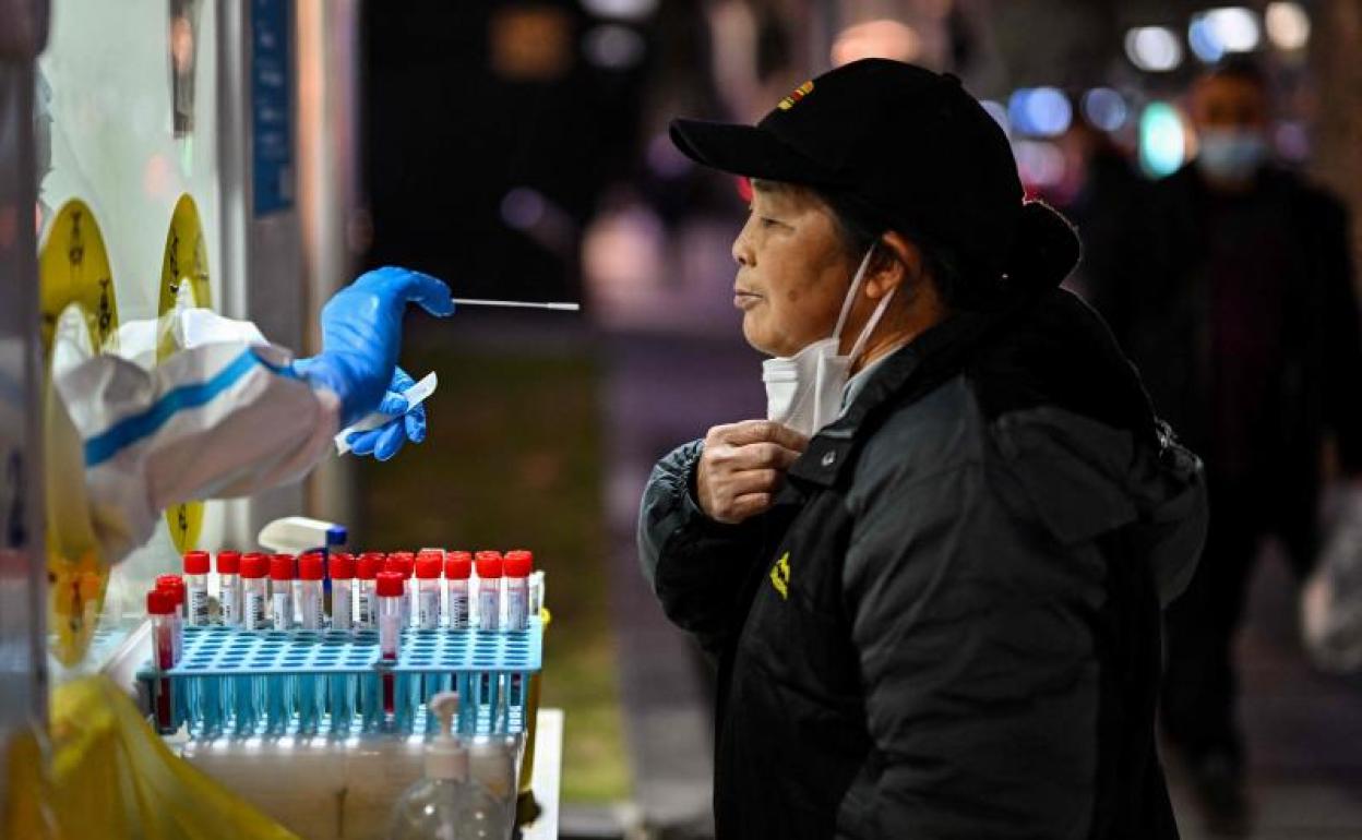 Un trabajador de la salud toma una muestra de una mujer para la prueba del coronavirus en el distrito de Huangpu, en Shanghái.