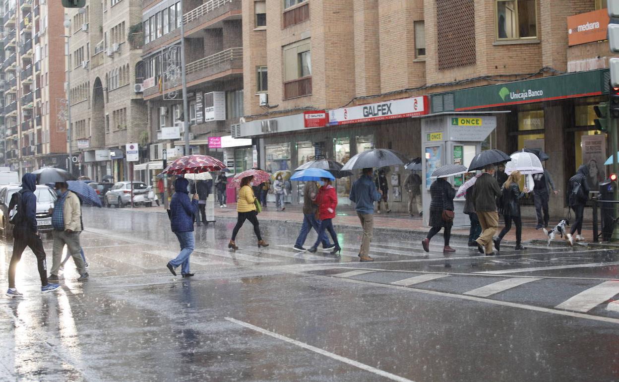 Imagen de archivo de gente caminando bajo la intensa lluvia en Cáceres.