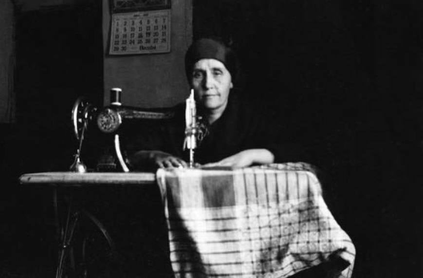Fotografía de 1936 (según el calendario de pared) de una mujer de luto cosiendo.