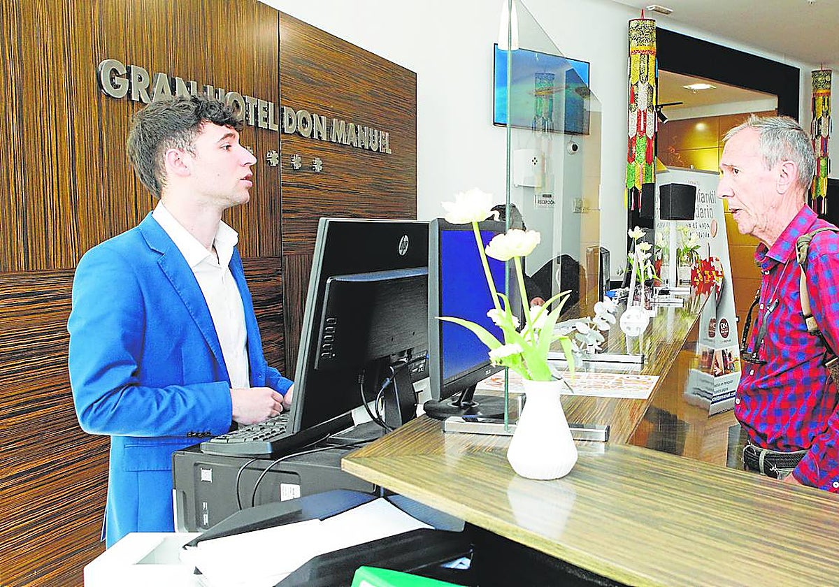 Un viajero es atendido en el mostrador de la recepción del hotel Don Manuel, que experimenta una fuerte demanda esta Semana Santa.