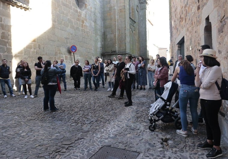 Un grupo de turistas atiende a las explicaciones de una guía ayer por la tarde en la Ciudad Monumental de Cáceres.