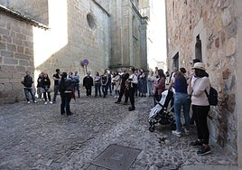 Un grupo de turistas atiende a las explicaciones de una guía ayer por la tarde en la Ciudad Monumental de Cáceres.