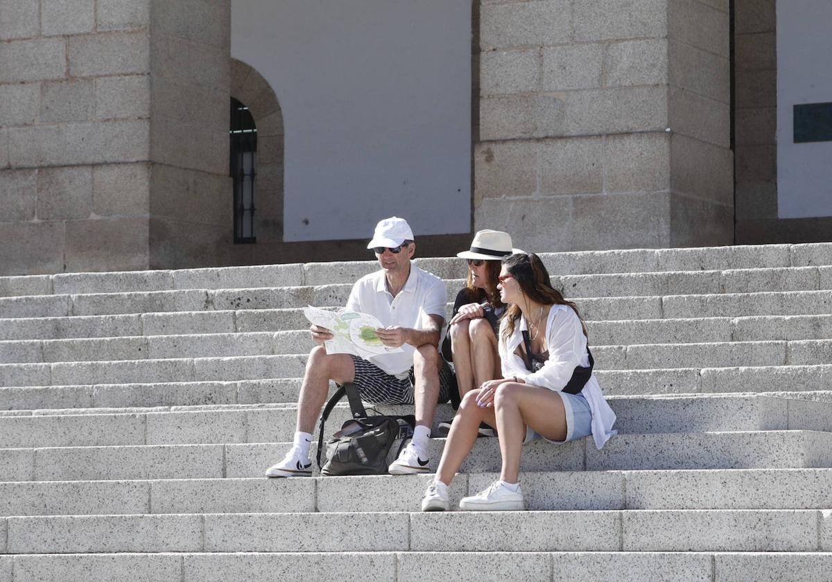 Turistas que visitan Cáceres estos días se protegen del sol con gorras, gorros y gafas.