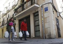 Dos personas pasan por delante de un apartamento turístico en Cáceres.