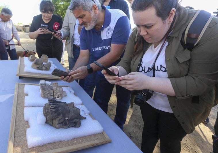 Dos personas fotografía con su móvil a las dos figuras humanas mejores conservadas halladas en el yacimiento de Guareña.