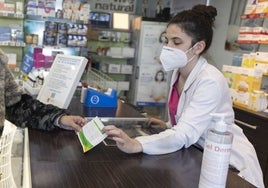 Una farmacéutica muestra un test covid a una clienta en una farmacia.