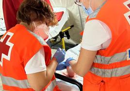 Voluntarios de Cruz Roja curan un pie a una persona este sábado en el ferial de Badajoz.