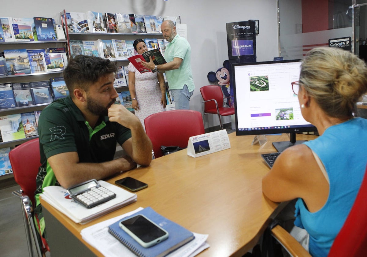 Los propietarios de la agencia CC. Travel, en Cáceres, atendiendo a dos clientes.