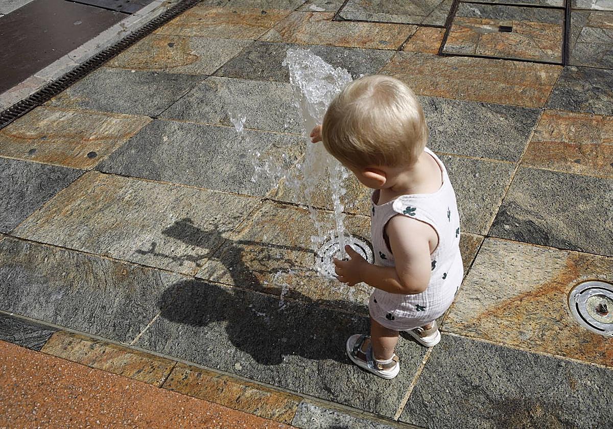 Un niño se refresca en una fuente en Cáceres.