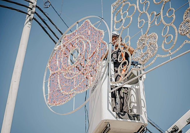 Un trabajador instalada alumbrado en el recinto ferial.